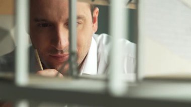 Kafkasyalı mimar mühendisinin yakın çekimi ev inşaatını denetlemek ve bina malzemelerini kontrol etmek. Proje yöneticisi modele dikkatlice bakarken kalemi işaret ediyor. Yönlendirici.