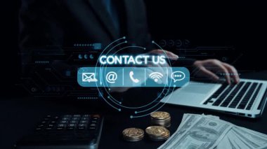 Bir iş adamı, para ile çevrili finansal verileri ve küresel ağ sembollerini gösteren bir dizüstü bilgisayarla etkileşime girer. Görüntü, modern finans ve dijital iletişimi yansıtıyor. Dörtgen