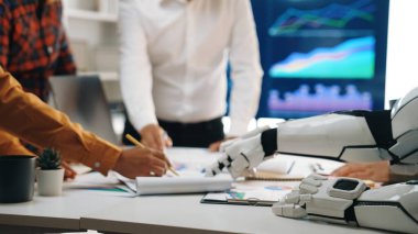 Veri analizi ve iş stratejisi gelişimi ile uğraşan insan profesyoneller ve robot kol arasındaki dinamik bir toplantı sahnesi. Noogenesis