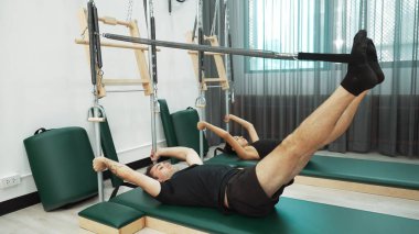 Bir grup müşteri, çekirdek dayanıklılığını ve bacak bağını geliştirmek için Cadillac reformatör makinesinde pilates egzersizleri yapıyor. Sağlıklı müşterilerin daha düşük poz verip kaldırma pozlarının üst görüntüsü. Sağlıklılık. Alışkanlık.