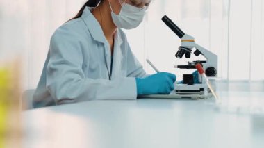 Laboratuvar kimya araştırmacısı mikroskop kullanarak yeni ilaç ya da tedavi geliştirir. Laboratuvar mikrobiyoloji ekipmanları ile bilimsel uzmanlık ile sağlık hizmetlerinin teknolojik gelişimi. Ağır çekim. Katı.