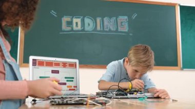 Kafkas akıllı çocuk kök teknoloji dersinde tornavida kullanarak ana tahtayı tamir ederken aynı zamanda gülümseyen öğrenci de dizüstü bilgisayar ekranı kodlu elektronik makineyi incelemek için birlikte çalışıyor. Pedagoji.