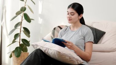 Kanepede oturan bir kadın ders kitabı okuyarak sosyal ve mesleki teknoloji bilgisini artırır ya da akıllı bir anne olmak için çocuk yetiştirir. Hayat boyu öğrenme konsepti. Uyumsuzluk.