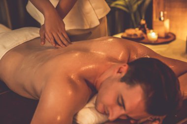 Beyaz erkek müşteri stres önleyici spa masajının keyfini çıkarıyor ve lüks otel ya da oteldeki ortam kaplıcalarında sıcak mum ışığında güzellik teniyle eğleniyor. Sessiz.