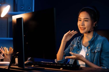 Sunucu kanalı Asyalı etkileyicisi canlı yayında konuşuyor. Sosyal medyada kulaklık takıyor, bilgisayar kaydı yapıyor, dinleyicileri selamlıyor ve Neon Modern Stüdyoları 'nda online olarak koçluk yapıyor. Taktik.