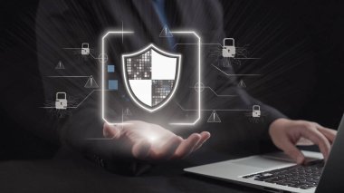 Bir işadamı, veri koruması ve çevrimiçi güvenliğin önemini vurgulayarak, kilitler ve uyarı simgeleriyle dolu bir dijital ortamda siber güvenliği simgeleyen parlak bir kalkan tutuyor. Dörtgen
