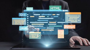 Bu resim, dizüstü bilgisayarın üzerinde kod sembolleri bulunan programlamaya uygulamalı bir yaklaşımı betimliyor. Modern dijital yeniliği temsil eden çeşitli programlama dilleri vurgulanmıştır. Dörtgen