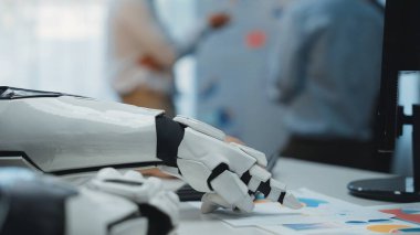 Robot bir elin modern bir ofisteki iş belgeleriyle etkileşime girerek iş yerindeki teknoloji ve otomasyonun entegrasyonunu gösteren yakın plan görüntüsü. Noogenesis
