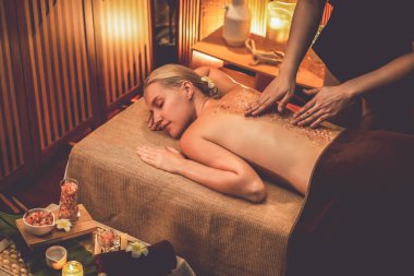 Lüks spa salonlarında sıcak mum ışığında cilt bakımı yaptıran kadın müşteri. Sağlık Spa vücut fırçasında tuz temizleme güzellik tedavisi. Sessiz.