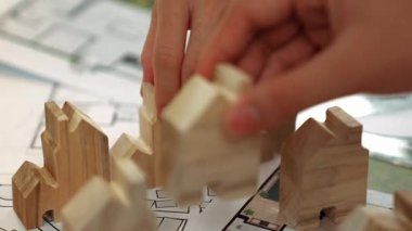 Mimar ve mühendis, mimari belgeyle birlikte masanın üzerine plan yapma, ölçüm araçlarının ofiste etrafa saçılması, ev yerleştirme için ahşap blok kullanımı konularını tartışıyor. - Yakın çekim. Tanımlama.