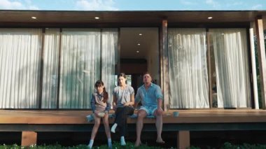 Şirin baba, anne ve kızı birlikte evin bahçesinde oturuyorlar. Ebeveynler, çevre farkındalığıyla ilgili genç nesli iletişim kurmak için açık hava aktivitelerini kullanırlar. Uyumsuzluk.