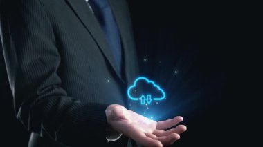 Bir işadamı, dijital yenilik ve bağlantıyı vurgulayarak, parlak bir arka plana karşı veri transferi ve güvenlik simgelerini vurgulayan bulut hesaplama teknolojisi sergiliyor. Dörtgen