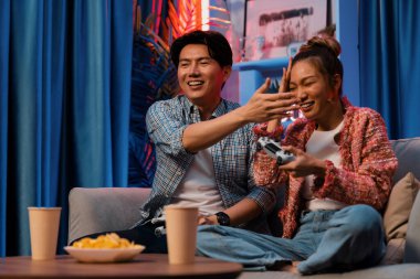 Oyun oynayan mutlu çiftin oturduğu kanepe joystickle oyun oynuyordu. Önden atıştırmalıklar ve kazanmak için gözlerini kapayan içkiler, evdeki modern neon ışıklı oturma odasında eğlenceli bir şekilde meydan okumaydı. İnfobahn.