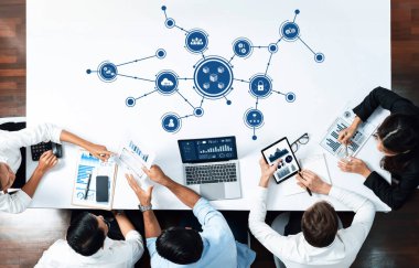 Gösterişli bir masada canlı bir iş görüşmesi teknoloji ve veri görselleştirmesi. Profesyoneller dizüstü bilgisayarlar ve tabletlerle ilgilenerek, modern bir çalışma alanında görüş ve stratejileri paylaşıyorlar. Dostluk