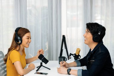 Gülümseyen radyo etkili sunucusu kulaklık takıyor kadın konuşmacı ile röportaj yapıyor sosyal medya internet sitesinden dinleyicilere bilgi paylaşıyor stüdyo kaydında sabah canlı yayın kanalı. İnfobahn.