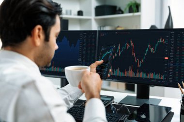 Elinde telefon dinamiğine odaklanan kahve fincanı tutan borsa yatırım ekranı veri analizini karşılaştırarak iç işlerinde yüksek kârlı finans teknolojisi pazarına yatırım yapıyor. Tahmin et..