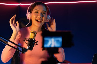 Yaratıcı yayın kanalı sosyal medyada pozitif podcasttaki dinleyicilerle birlikte müziği dinliyor, pastel renkli kulaklıklar takıyor, neon stüdyodaki kameraların mikrofon kayıtlarını kullanıyor. Taktik.