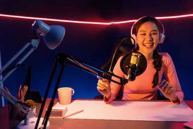 Geceleri podcast 'te olumlu konuşmalar yapan, pembe neon ışıklı modern stüdyoda sunum için dizüstü bilgisayar kullanan, gülümseyen, genç, güzel Asyalı bir etkileyiciydi. Taktik.