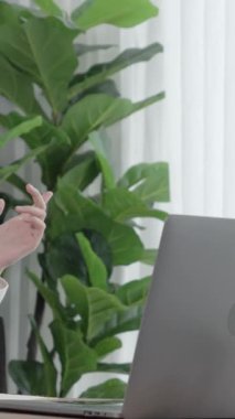 Masasında dizüstü bilgisayarla çalışan kulaklık ve mikrofon takan Asyalı müşteri destek operatörü. Hevesli kadın çalışanlar müşteri hizmetleri sunuyor, destekleyici çağrı merkezi temsilcisi müşterilere yardım ediyor.