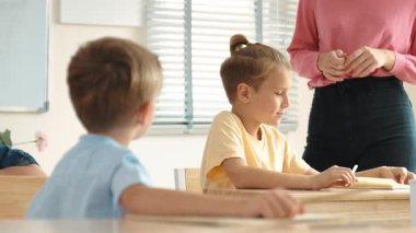 Beyaz bir çocuk ödevlerini yaparken ve açıklama dinlerken güzel bir öğretmen sınavı açıklıyor. Sınıfta not alırken ya da kağıda cevap yazarken öğretmenine bakan sevimli bir çocuk. Pedagoji.