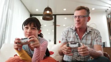 Granddaughter teaching grandfather play console game, entertainment hobby. Old senior use technology communicate with new generation kid cross generation gap strengthen family bond. Divergence.