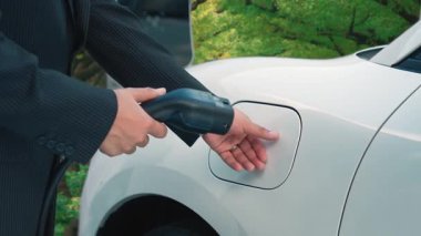 Çevre bilincini artırmak için sürdürülen ilerici kampanya, yeşil ormandaki şarj istasyonundan elektrik enerjisiyle çalışan elektrikli aracını şarj ediyor. Gelecekteki otomobiller için EV otomobil.