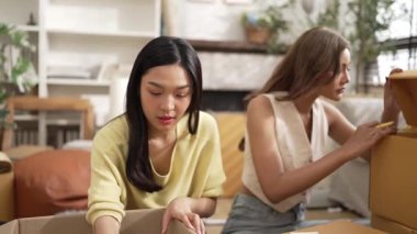 Çekici bir oda arkadaşı oturma odasında paket paketlerken pakette konum yazıyor. Mutlu satıcı birlikte çalışıyor ve teslimat paketini hazırlıyor. Girişimci kargo kutusu paketliyor. Myrmidon.