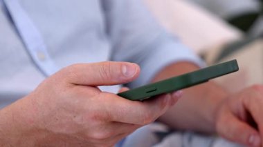 Orta yaşlı bir adam oturma odasındaki koltukta oturur telefon arama verilerini kullanır çocukları iyi bir yetişkin baba ya da eğlence olarak yetiştirir. İşadamı teknolojiyi kolaylık için kullanır. Uyumsuzluk.