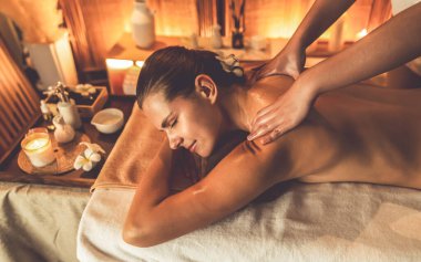 Beyaz kadın müşteri stres önleyici spa masajının keyfini çıkarıyor ve lüks otel ya da otelde sıcak mum ışığında güzellik teniyle eğleniyor. Sessiz.