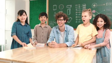 Profesyonel Kafkas öğretmeni ve çeşitli öğrenciler kameraya bakarken mutlu okul çocuğu gülümsüyor. Sınıfın önünde dururken gülümseyen bir grup çok kültürlü çocuk. Eğitim. Pedagoji.