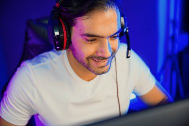 Dijital neon ışıklı stüdyo odasındaki sosyal medya uygulamasında diğer canlı yayınlarla iletişim kurmak için kulaklık ve mikrofon kullanan takım üyeleriyle konuşan akıllı oyun flaması portresi. Tahmin et..