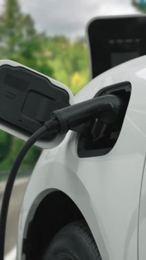 Elektrikli araç konsepti, yeşil çevre için yenilenebilir ve temiz enerjiyle çalışan EV otomobilinin varış noktasına ulaşmadan önce ormandaki şarj istasyonunun enerjisini şarj etmek için durur..