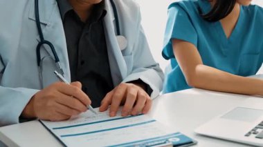 Hastane masasında birlikte çalışan ve tıbbi tedavi planlayan çeşitli profesyonel sağlık görevlileri. Takım çalışması başarılı hastalıklara ve hastalıklara yol açar. Ağır çekim. Katı.