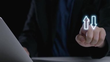 Bir işadamı, dijital çalışma alanında etkili bir strateji ve karar verme mekanizması için yukarı ve aşağı ok atarak, bir dizüstü bilgisayardaki kalite ve maliyet ölçümlerini analiz eder. Dörtgen