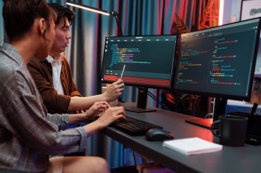 Bilgi teknolojisi geliştiricileri modern ofisteki neon ışık odasında verileri çevrimiçi olarak çalıştıran akıllı web sitesi geliştirme kodlayıcı sistemine işaret ediyorlar. İnfobahn.