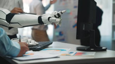Modern ofis ortamında bilgisayar ekranını gösteren robot bir el, iş haritalarını ve veri analizlerini gösteriyor, otomasyon ve yenilikleri vurguluyor. Noogenesis