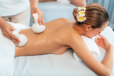 Sıcak bitkisel top spa masaj vücut tedavisi, masör nazikçe bitki torbasını çift müşteri vücuduna bastırıyor. Aromaterapi dinlenme sükuneti ve sükuneti kaplıca salonundaki atmosferi aydınlatıyor. Sessiz.