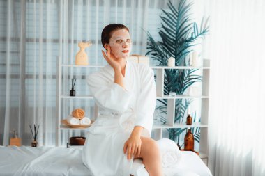 Kaplıca salonunun sakin, modern gün ışığı atmosferi, kadın müşteri poz veriyor ve yüz maskesi ile gençleştiriyor. Yüz bakımı ve güzellik kozmetolojisi prosedürü. Sessiz.