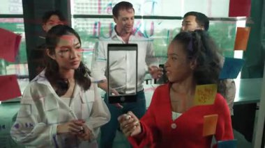 Profesyonel iş adamları, cam duvarda yaratıcı fikirleri paylaşmak için yapışkan notlar kullanarak pazarlama fikrini araştırıyor. Bir grup farklı iş adamları strateji hakkında tartışıyorlar. - Yakın çekim. Yönlendirici.