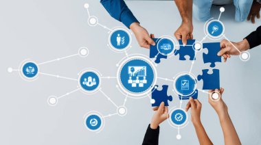 İş adamları, modern bir ofis ortamında takım çalışmasını ve stratejik planlamayı sembolize ederek, yenilik ve büyüme çözümlerini vurgulayarak işbirliği içinde bir bulmaca üzerinde çalışıyorlar. Dostluk