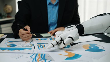 Modern bir ofis ortamında insan ve robot takım çalışmasının büyüleyici bir sahnesi, veri analizi ve iş dünyası için teknolojik çözümlerin altını çiziyor. Noogenesis