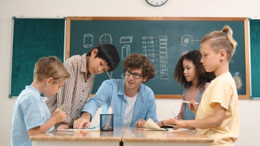 Zeki öğretmen, çeşitli çocuklar sınıf çalışması yapmak için birlikte çalışırken farklı çocukların zihin haritası çizdiği fikri açıklıyor. Çekici eğitmen öğretmek ve çalışmak hakkında konuşmak. Pedagoji.