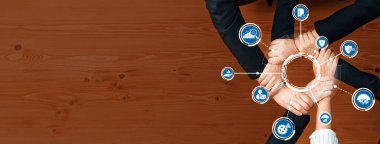 Çeşitli ellerin konsept simgeleri etrafında işbirliğine katılması, ahşap bir masada takım çalışması ve yönetim stratejilerini sembolize etmesi. İş teması için ideal. Dostluk