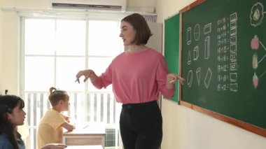 Kafkasya öğretmeni öğrencilerden sınıfın önünde soruyu cevaplamak için ellerini kaldırmalarını rica ediyor. İlkokulda matematik dersinde yazdıkları için çocukları çağıran çekici eğitmen. Pedagoji.