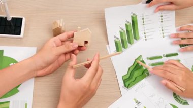 Mükemmel iş adamları, karbon ayak izini azaltmak, Dünya 'yı kurtarmak için grafik, yel değirmeni, ev ve ağaç modelini kullanarak yeşil enerjili eko ev projesinde işbirliği yaparlar. Eline odaklan. Tanımlama.