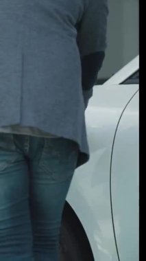 İlerici baba-kız elektrikli araç şarj istasyonundan fiş takıyor. Geleceğin çevre dostu arabası yenilenebilir temiz enerji kaynağıyla çalışıyor..