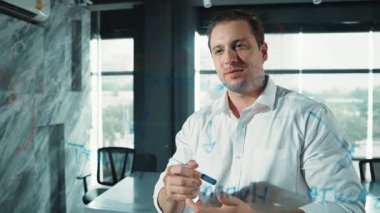 Akıllı iş adamı cam tahtanın önünde bir proje başlatmayı düşünüyor. Gülümseyen erkek proje yöneticisi yaratıcılık pazarlama stratejisini gösteren renkli yapışkan notlara bakıyor. Yönlendirici.