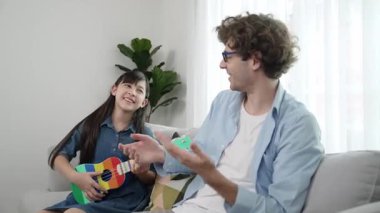 Mutlu bir babanın, ukulele çalan ve şarkı söyleyen akıllı kızına bakışının arkası. Mutlu baba motive oldu ve Amerikalı liseli kızı gitar çalmaktan zevk almaya teşvik etti. Aile eğlencesi. Pedagoji.