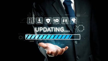 Takım elbiseli bir iş adamı, modern işletmelerde teknolojik gelişmeyi ve yeniliği sembolize eden bir ilerleme çubuğunu gösteren dijital bir arayüz tutuyor. Dörtgen