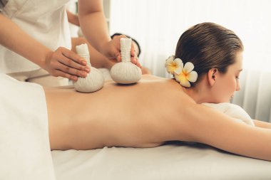 Sıcak bitkisel top spa masaj vücut tedavisi, masör nazikçe bitki torbasını çift müşteri vücuduna bastırıyor. Aromaterapi dinlenme sükuneti ve sükuneti kaplıca salonundaki atmosferi aydınlatıyor. Sessiz.